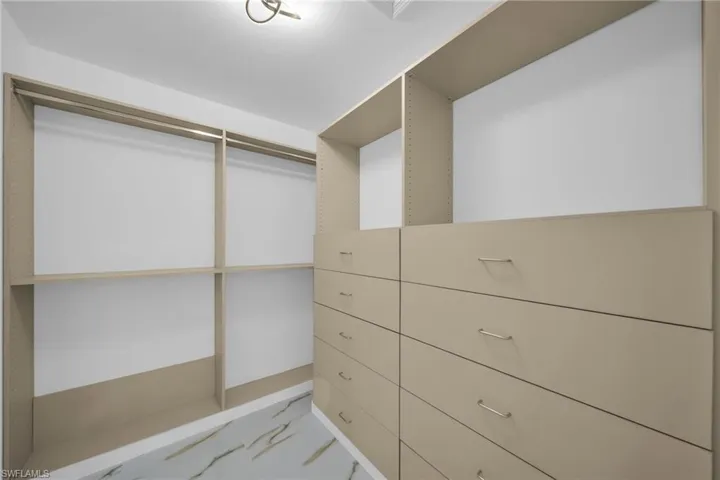 Walk in closet with light marble finish floors