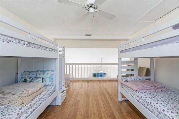 Bedroom with a textured ceiling, wood finished floors, and ceiling fan