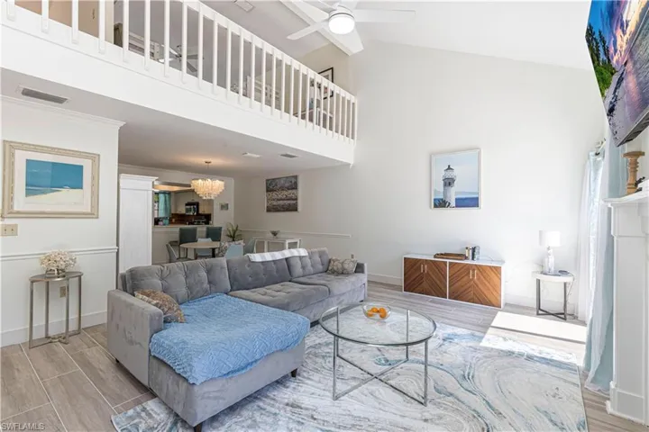 Living area with wood tiled floors, high vaulted ceiling, ceiling fan, and a chandelier