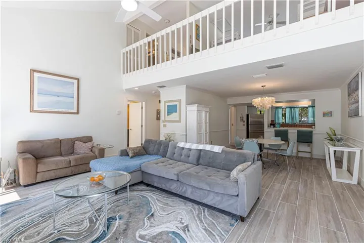 Living room featuring a high ceiling, wood tiled floors, a ceiling fan, and a chandelier