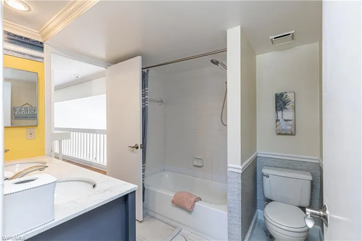 Bathroom with vanity, shower / washtub combination, a wainscoted wall, and crown molding