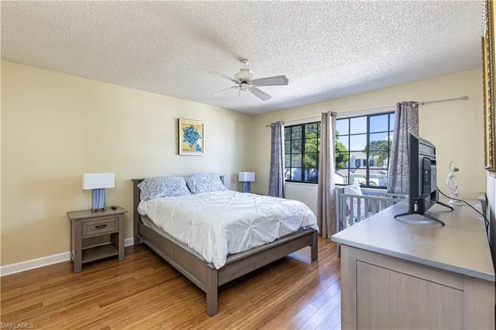 Bedroom featuring light wood-type flooring, a textured ceiling, and a ceiling fan