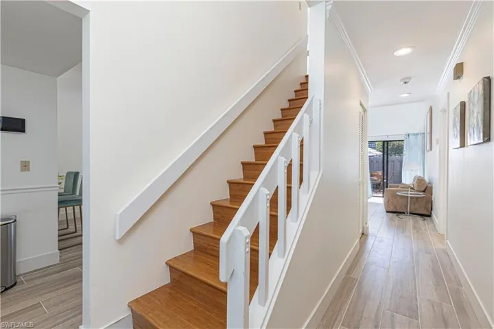 Stairs with wood finish floors, crown molding, and recessed lighting