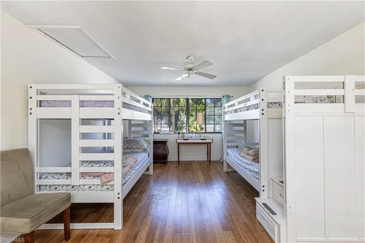 Bedroom featuring a textured ceiling, hardwood / wood-style floors, and attic access