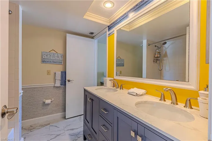 Bathroom featuring crown molding, double vanity, and marble finish flooring