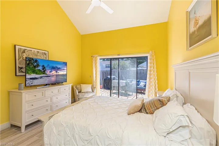 Bedroom with access to exterior, light wood finished floors, a ceiling fan, and high vaulted ceiling