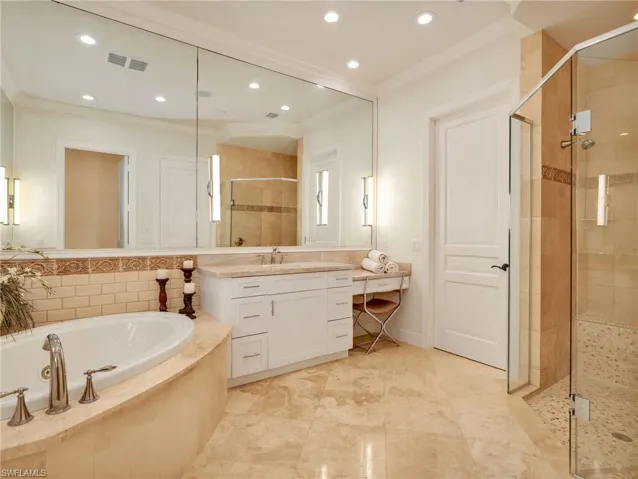Owner's Suite Bathroom featuring a large jacuzzi tub, a glass-enclosed shower with stone tile, and a full-wall mirror.