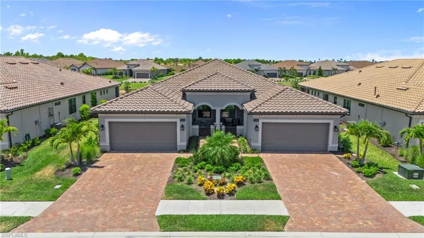 Mediterranean / spanish home featuring a garage, a residential view, a tiled roof, and decorative driveway