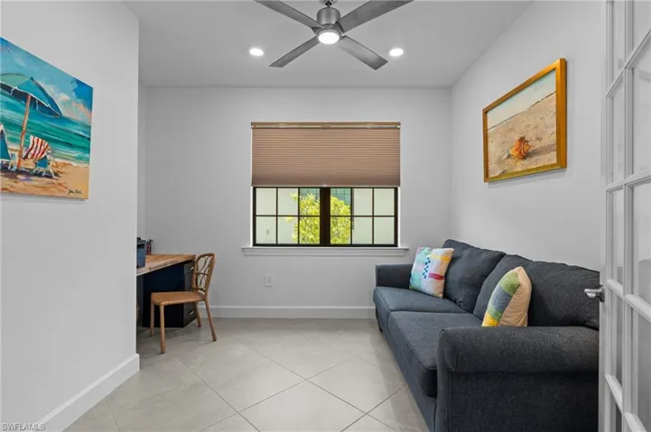 Living area with light tile patterned flooring, baseboards, ceiling fan, and recessed lighting