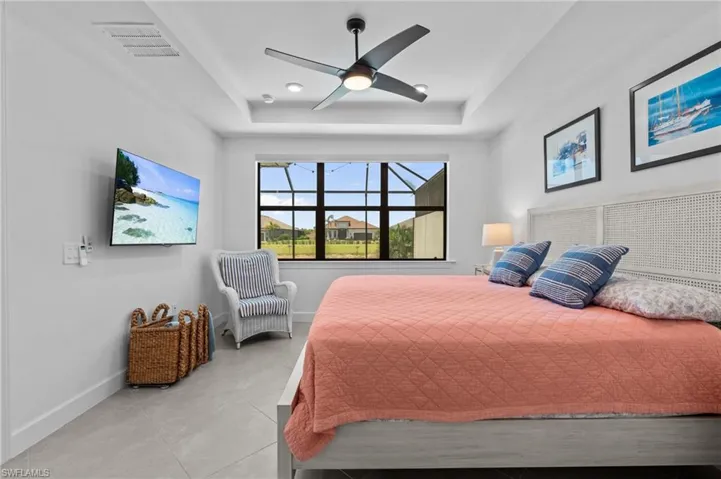 Bedroom with a tray ceiling, baseboards, light tile patterned floors, and ceiling fan