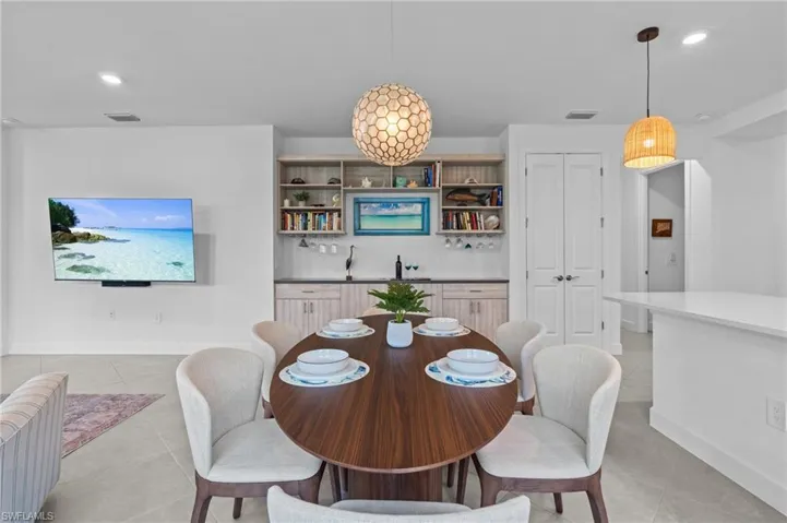 Dining room with light tile patterned floors, baseboards, bar with sink, and recessed lighting