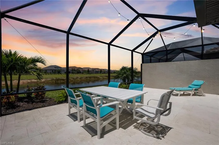Patio terrace at dusk featuring a water view, outdoor dining area, and a lanai