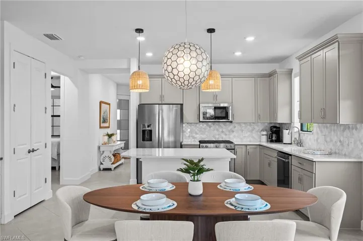 Kitchen with appliances with stainless steel finishes, gray cabinetry, a sink, light countertops, and tasteful backsplash
