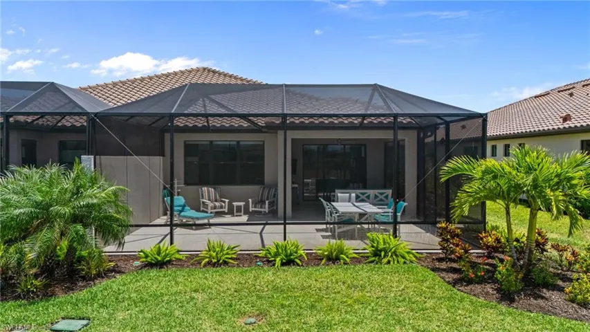 Back of property with a patio, a yard, stucco siding, and a tile roof