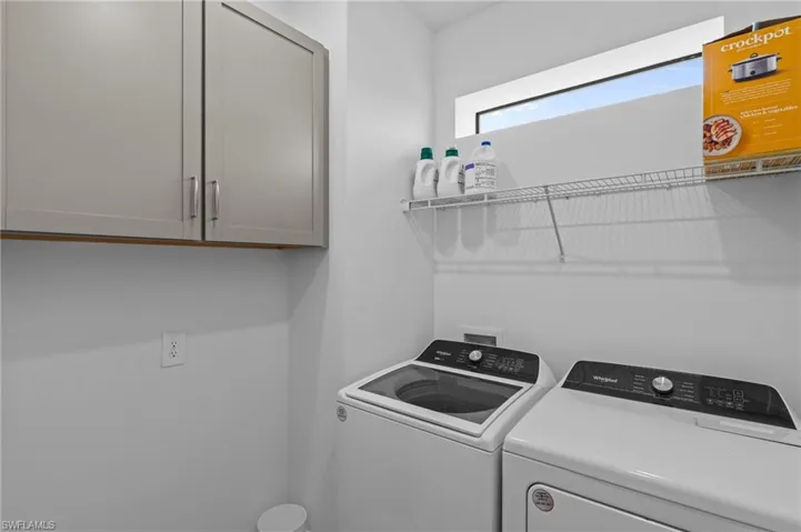Clothes washing area featuring washing machine and clothes dryer and cabinet space