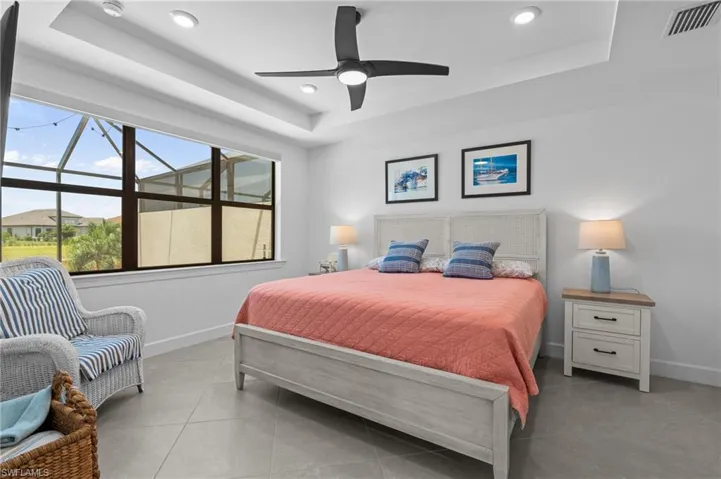 Bedroom with a tray ceiling, baseboards, ceiling fan, and recessed lighting