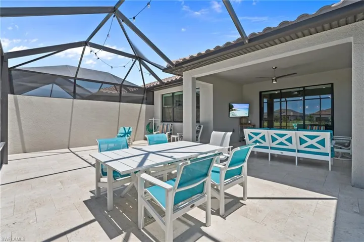 View of patio featuring outdoor dining area, a ceiling fan, a lanai, and an outdoor hangout area