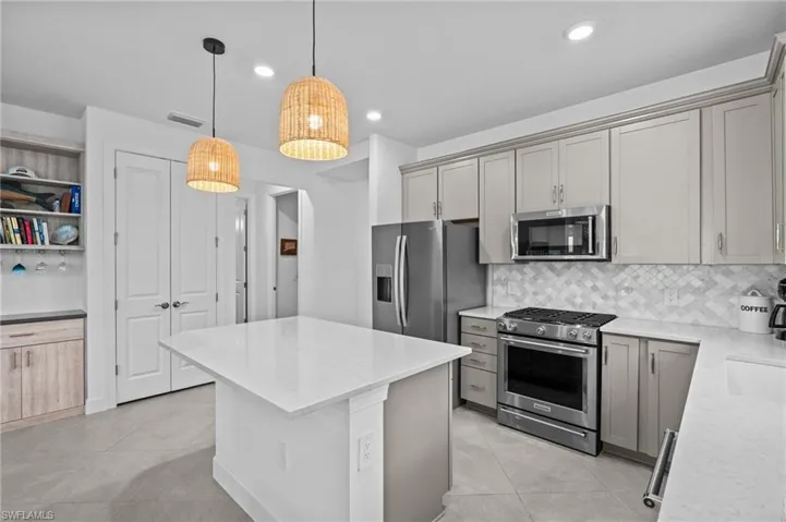 Kitchen with stainless steel appliances, light tile patterned floors, gray cabinets, and recessed lighting
