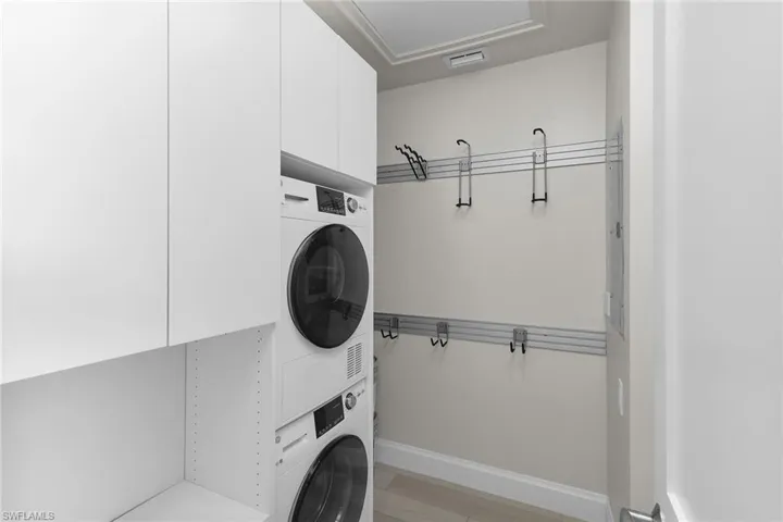Laundry room with stacked washing machine and dryer and baseboards