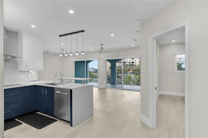 Dual tone kitchen featuring pendant lighting, dual tone cabinetry, a peninsula, light stone countertops, and dishwasher