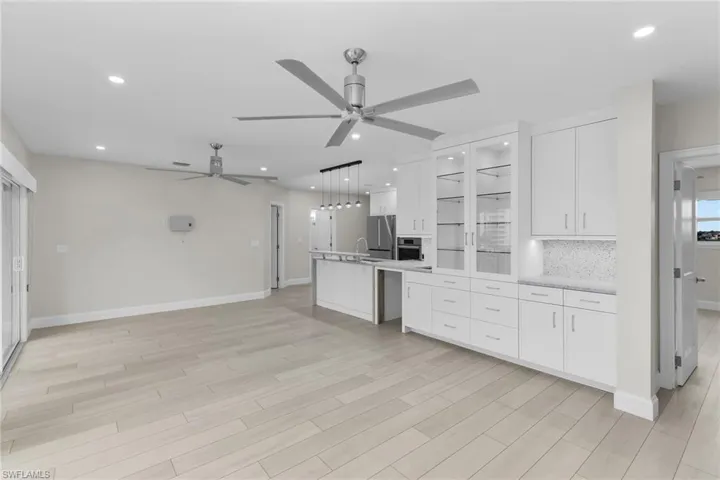 Kitchen with white cabinetry, glass insert cabinets, hanging light fixtures, and ceiling fan