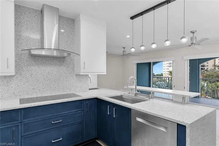 Kitchen featuring light stone countertops, dual tone cabinetry, decorative light fixtures, stainless steel dishwasher, and a ceiling fan