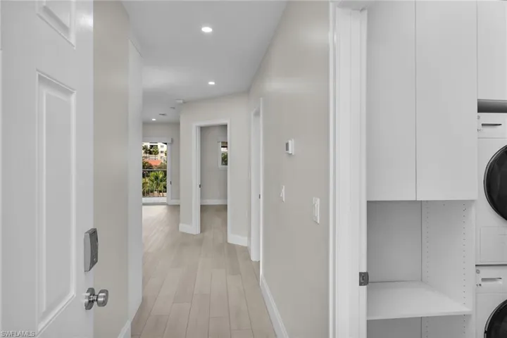 Hall featuring stacked washing machine and dryer, light wood finished floors, and recessed lighting