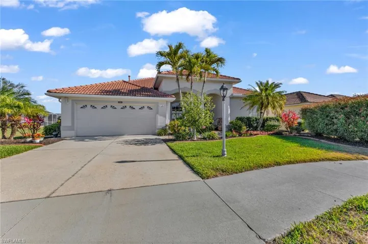 Mediterranean / spanish house with a garage, concrete driveway, a front yard, stucco siding, and a tiled roof