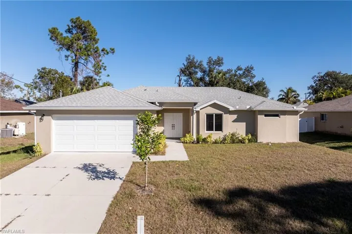 Ranch-style home featuring stucco siding, a front lawn, concrete driveway, an attached garage, and roof with shingles