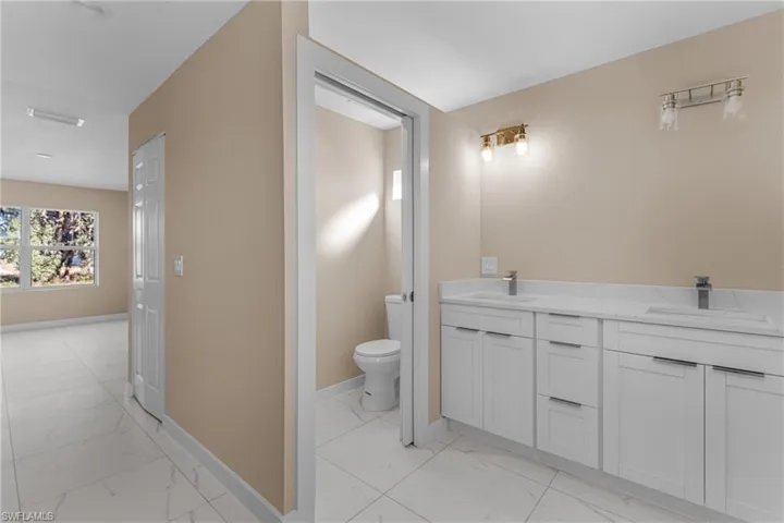 Bathroom featuring double vanity and light marble finish floors