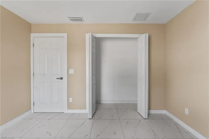 Unfurnished bedroom featuring light marble finish floors and a closet