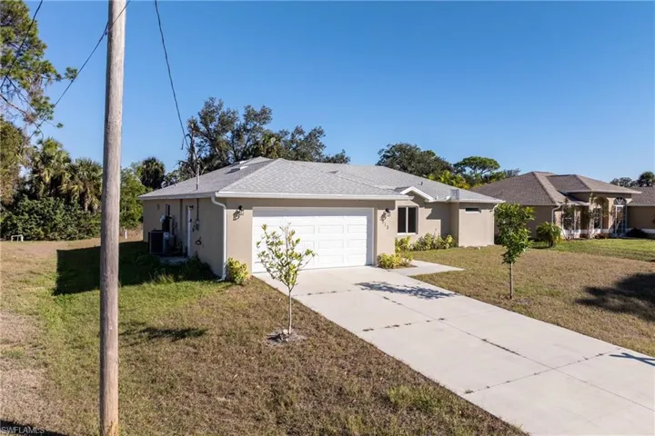 Single story home featuring stucco siding, a front lawn, a garage, and driveway