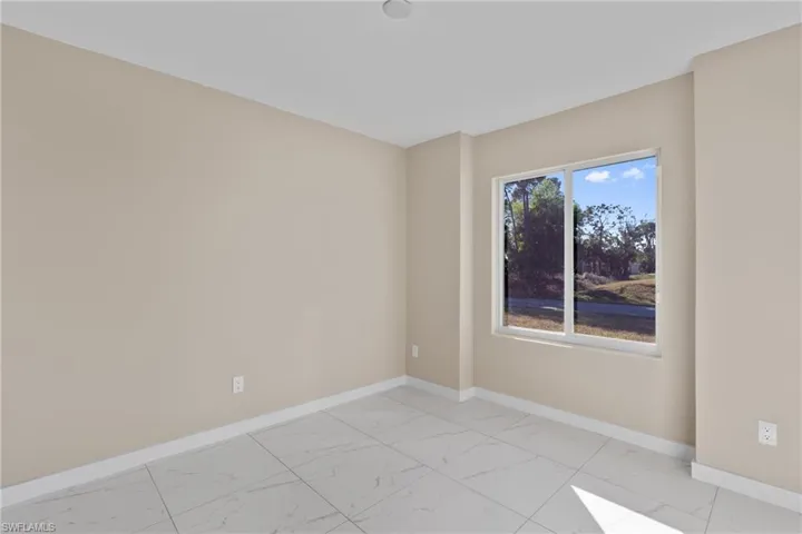 Spare room featuring baseboards and light marble finish floors