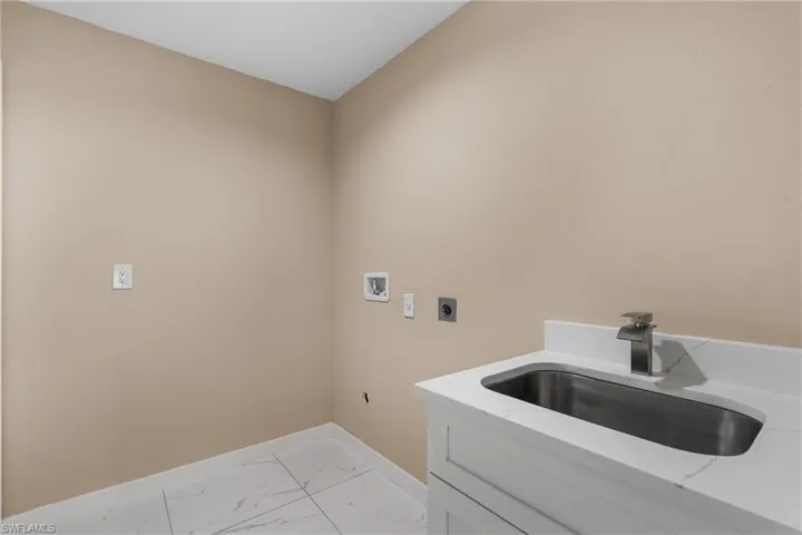 Washroom with electric dryer hookup, light marble finish flooring, and washer hookup