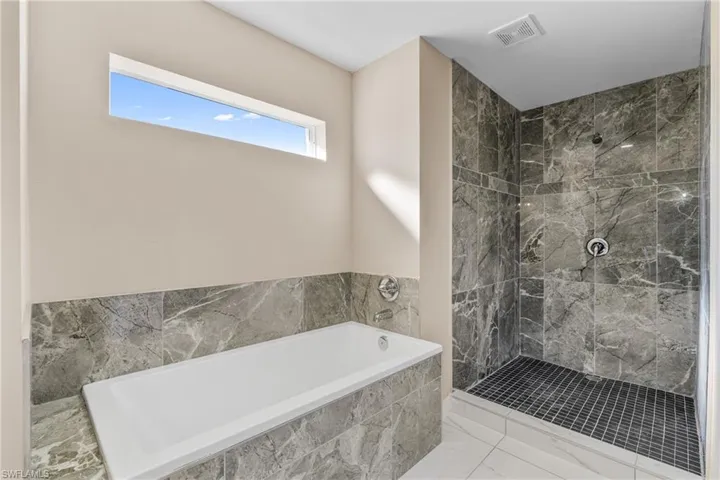 Full bathroom with a bath, marble look tile flooring, and a shower stall