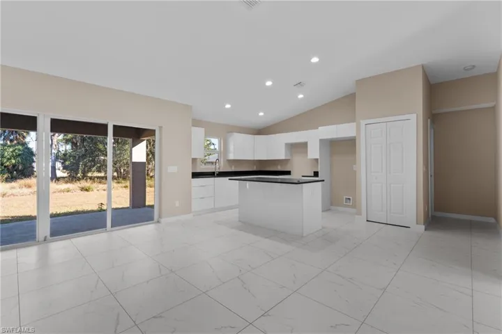 Kitchen featuring recessed lighting, dark countertops, white cabinetry, lofted ceiling, and a center island