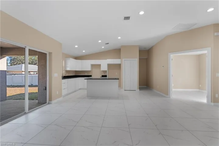 Kitchen with recessed lighting, white cabinets, open floor plan, vaulted ceiling, and a kitchen island