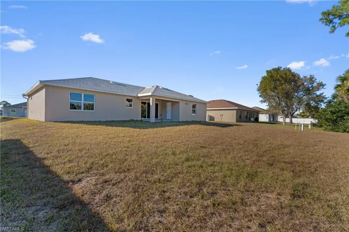 Rear view of house featuring a yard, stucco siding, and a patio