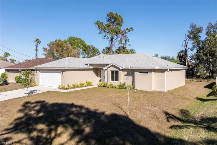 Ranch-style home featuring driveway, a garage, a front yard, and stucco siding