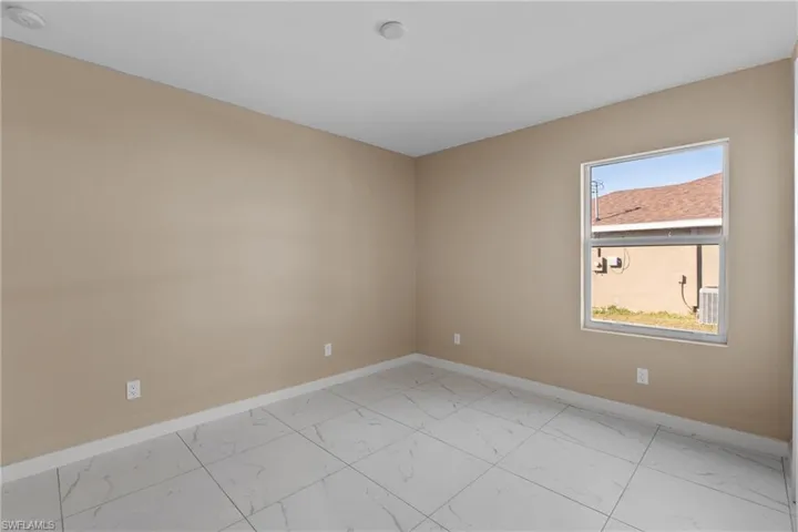 Unfurnished room featuring baseboards and light marble finish floors