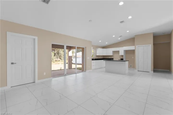 Unfurnished living room featuring recessed lighting, vaulted ceiling, and light marble finish flooring