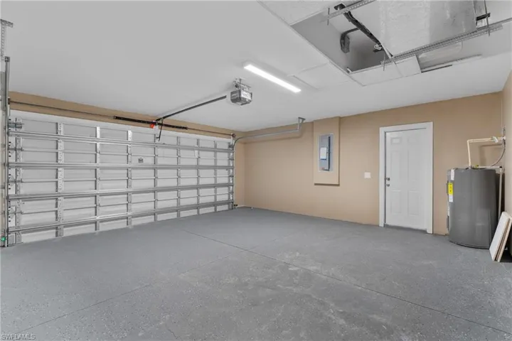 Garage featuring water heater, a garage door opener, and electric panel