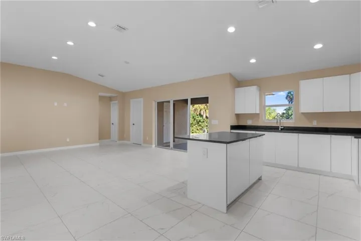 Kitchen with recessed lighting, white cabinets, light marble finish floors, modern cabinets, and a kitchen island