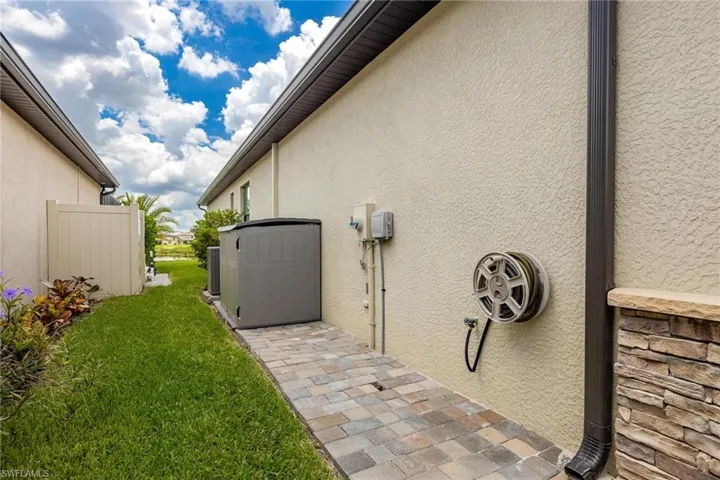 View of side of property featuring central AC unit and a lawn