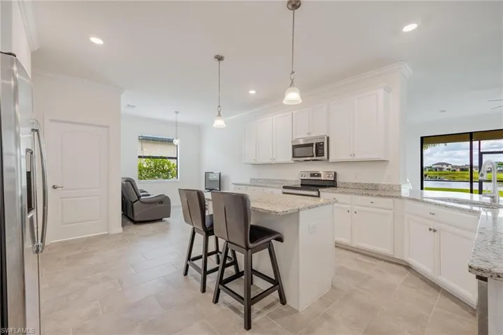 Kitchen featuring decorative light fixtures, stainless steel appliances, white cabinetry, sink, and light tile floors