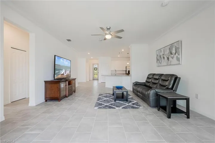 Tiled living room with ornamental molding and ceiling fan