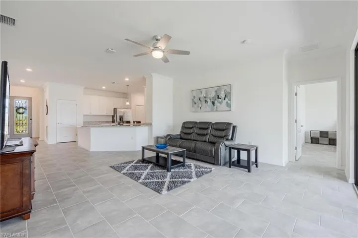 Tiled living room featuring ceiling fan and crown molding