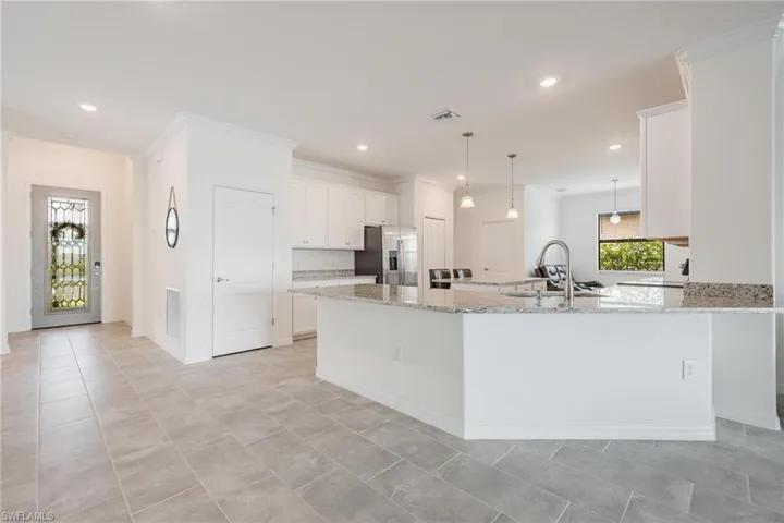 Kitchen featuring sink, stainless steel fridge with ice dispenser, light tile flooring, and white cabinetry