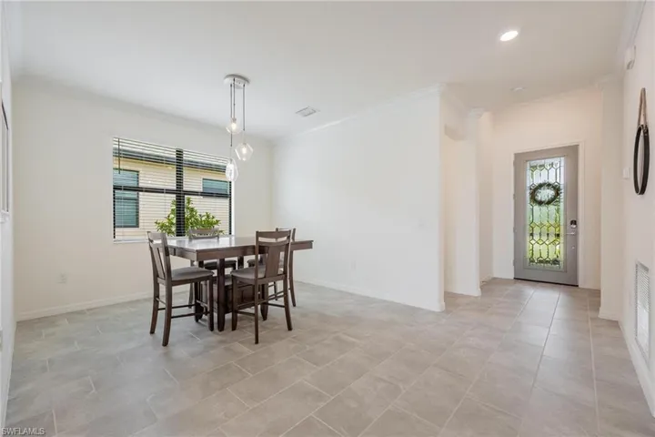 Dining room with a wealth of natural light, light tile flooring, and crown molding