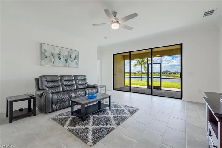 Living room featuring ceiling fan, light tile floors, and crown molding